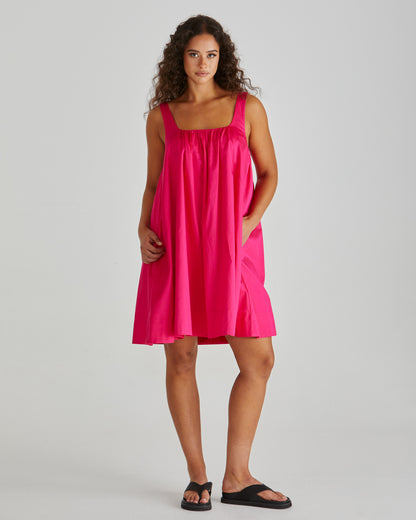SASS Ellis Mini Dress in hot pink with scalloped wide hem and side pockets. Lady wearing dress with wide straps. Available at Loloma Living.