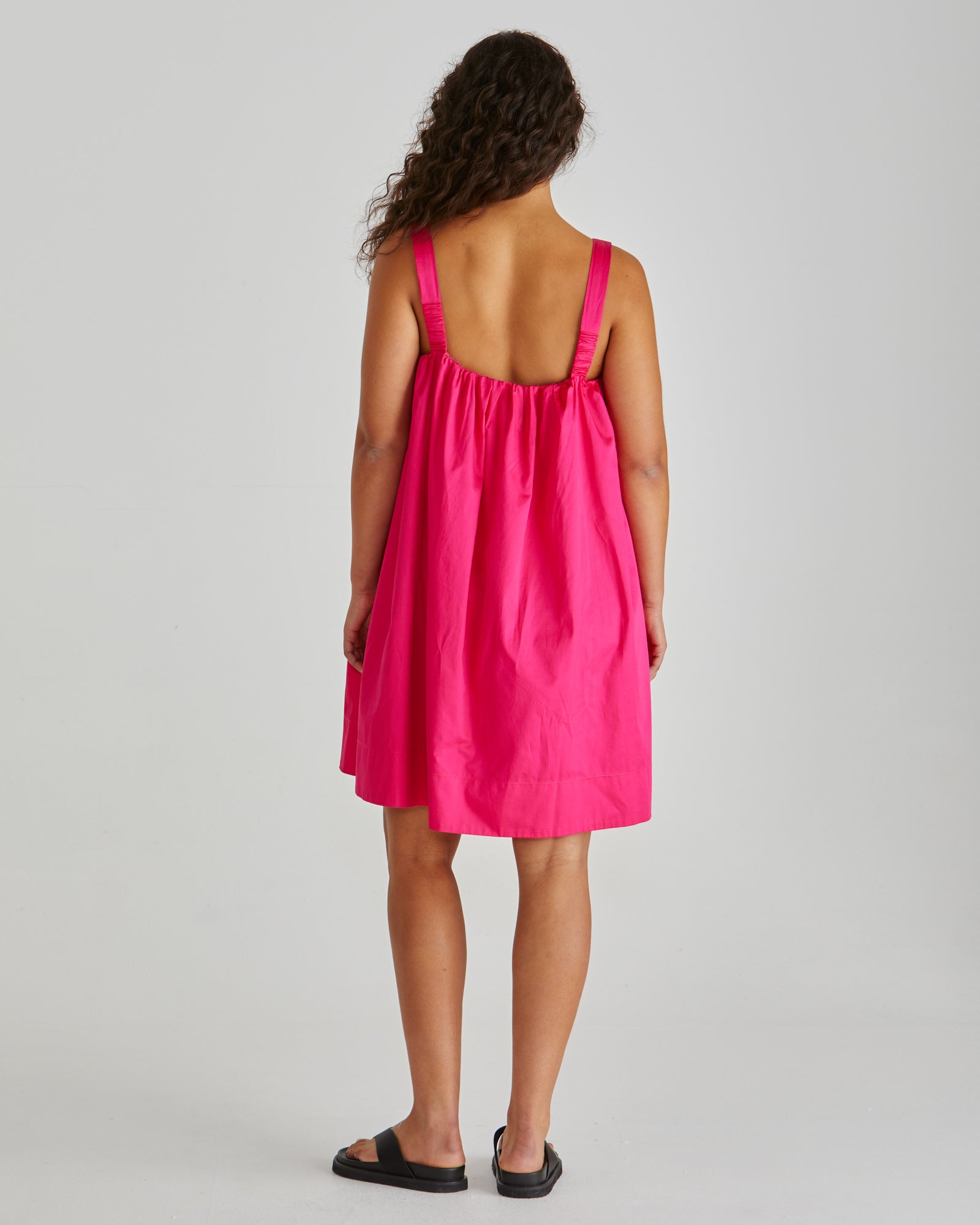 SASS Ellis Mini Dress in hot pink with scalloped wide hem and side pockets. Back view with wide straps. Available at Loloma Living.