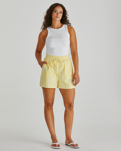 Lady wearing the SASS Zane Short in yellow white stripe with elastic waistband, drawcord and side pockets. Available at Loloma Living, Tamborine Mountain.
