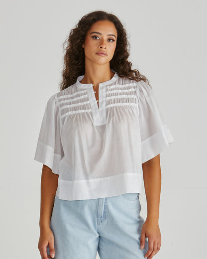 Lady wearing the SASS Pammi Blouse in white with ruffle detail, button front and wide hem. Available at Loloma Living, Tamborine Mountain. Stockist of SASS and Betty Basics.

