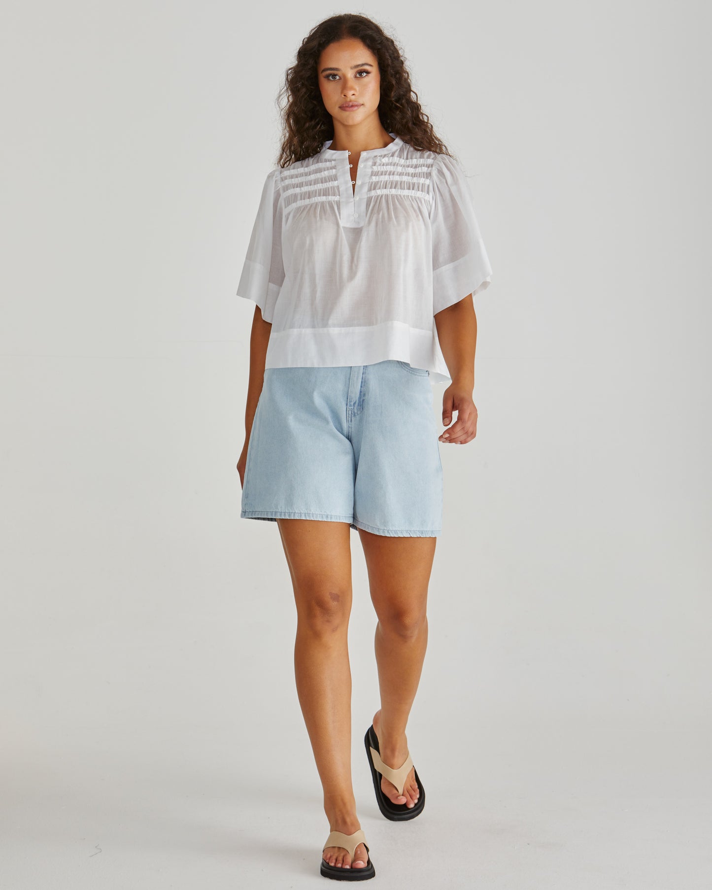 Lady wearing the SASS Pammi Blouse in white with ruffle detail, button front and wide hem. Available at Loloma Living, Tamborine Mountain. Stockist of SASS and Betty Basics. Fast postage.

