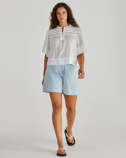 Lady wearing the SASS Pammi Blouse in white with ruffle detail, button front and wide hem. Available at Loloma Living, Tamborine Mountain. Stockist of SASS and Betty Basics. Fast postage.
