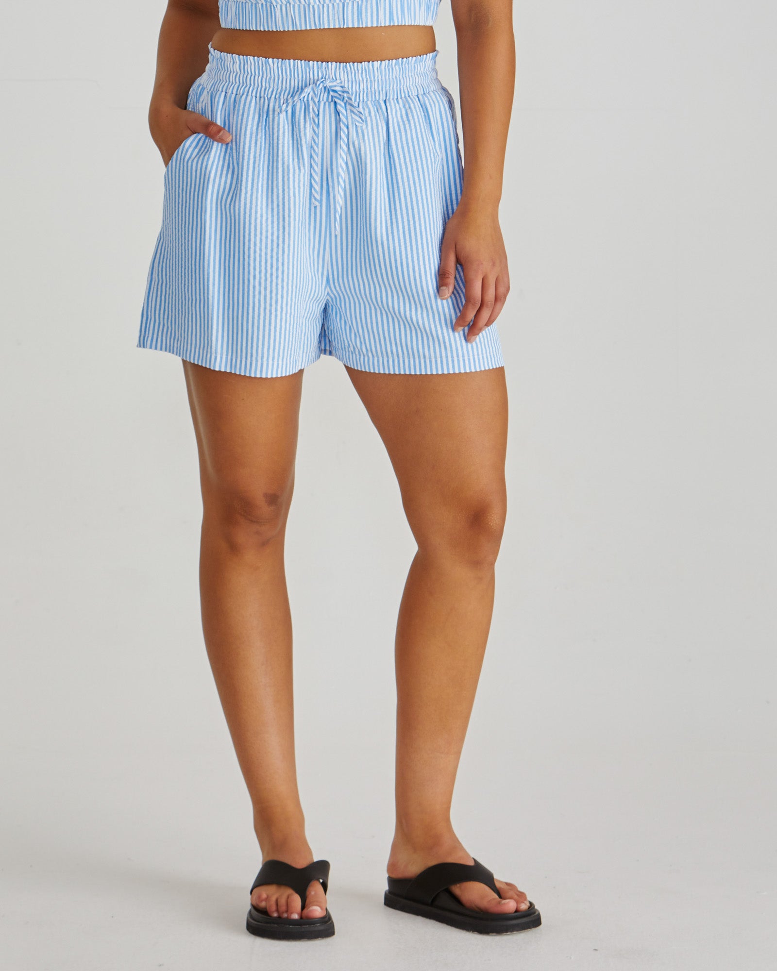 Close up of Lady wearing the SASS Alani Short in blue white stripe seersucker with elastic waist, drawcord and side pockets. Available at Loloma Living Tamborine Mountain - stockist of SASS and Betty Basics.

