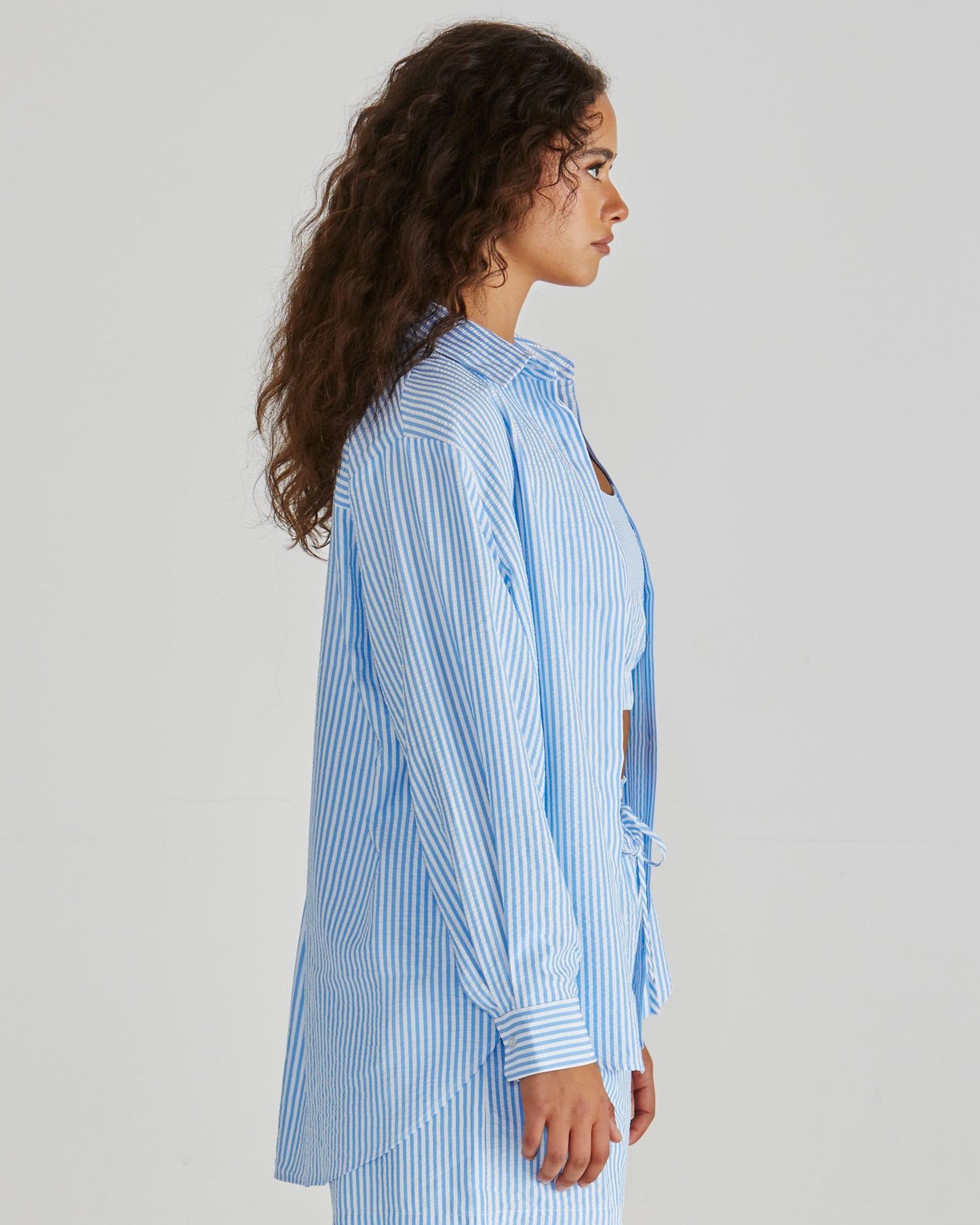 Side view of Lady wearing the SASS Alani Shirt in Blue White Stripe seersucker with concealed placket and dropped shoulder. Available at Loloma Living, Tamborine Mountain - stockist of SASS and Betty Basics.