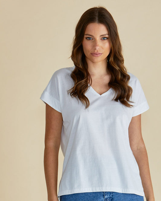 Woman wearing a white t-shirt and blue jeans against a beige background