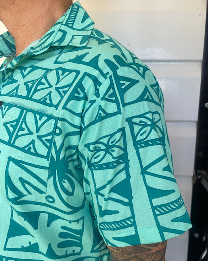 man wearing island shirt with pacific print in teal colour showing a close up of the sleeve and collar. Available at Loloma Living, Tamborine Mountain.